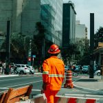 Trabalhador da construção civil caminha por uma rua movimentada de São Paulo durante o horário comercial.