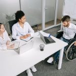 Grupo diverso de colegas participa de uma reunião de trabalho em um ambiente corporativo.