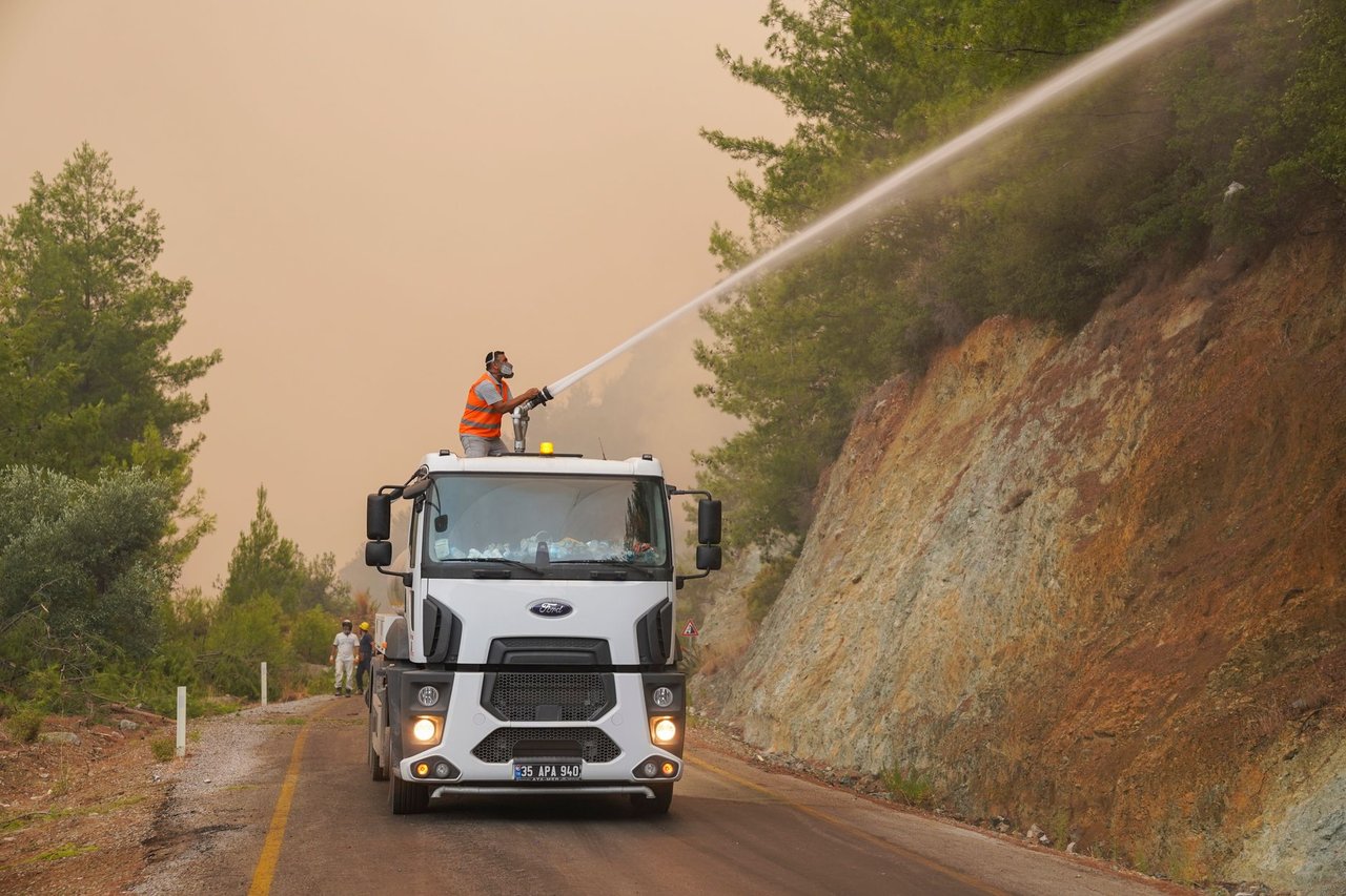 Bombeiros usam o canhão de água de um caminhão para combater um incêndio florestal.