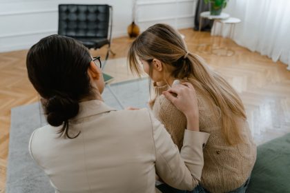 Duas mulheres sentadas em ambiente interno, em um momento de apoio e empatia.