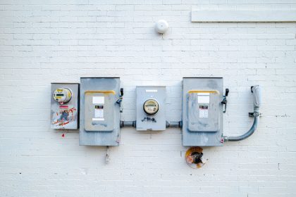 Medidores e caixas de energia instalados em uma parede de tijolos brancos.