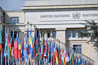 Bandeiras de vários países diante do escritório das Nações Unidas em Genebra, simbolizando a cooperação internacional.